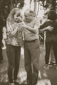 Elderly man dances with female caregiver